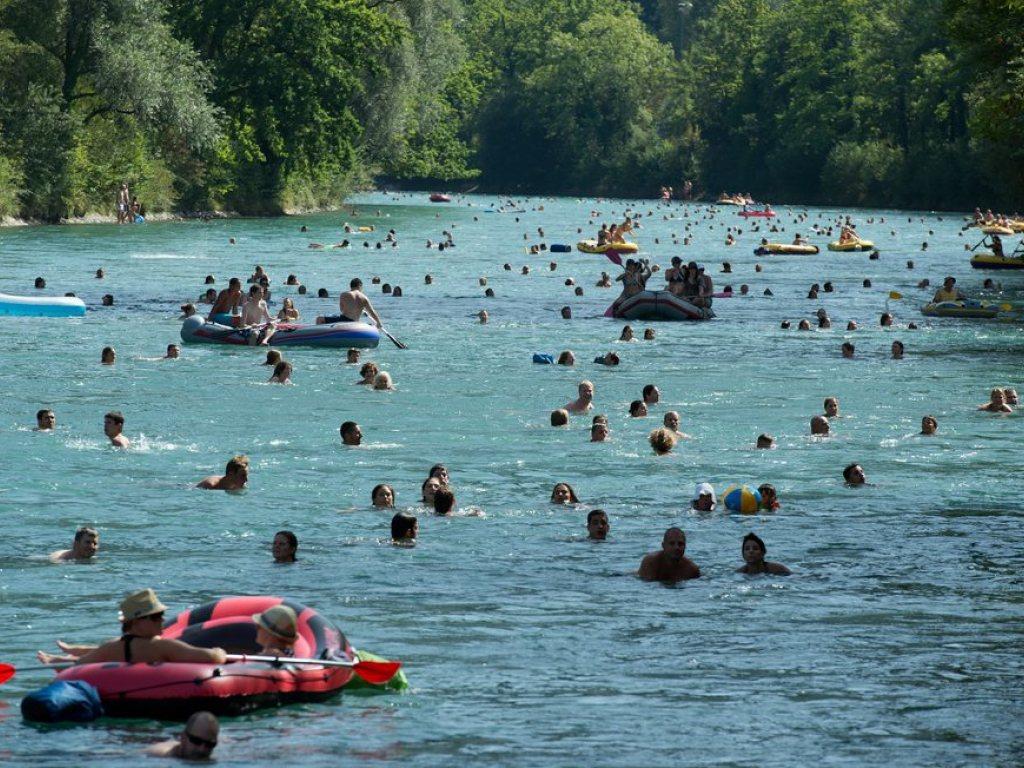 Ein Fluss voller Schwimmer und Boote.