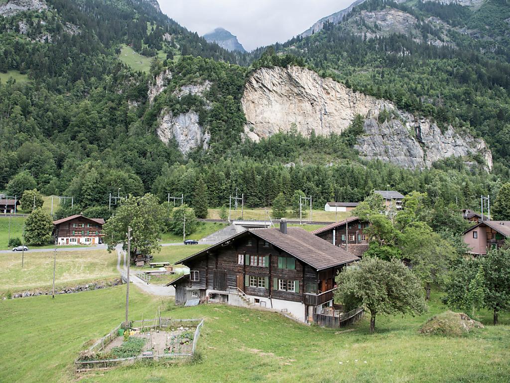 Ein paar Häuser aus Holz, im Hintergrund ein Felsen.