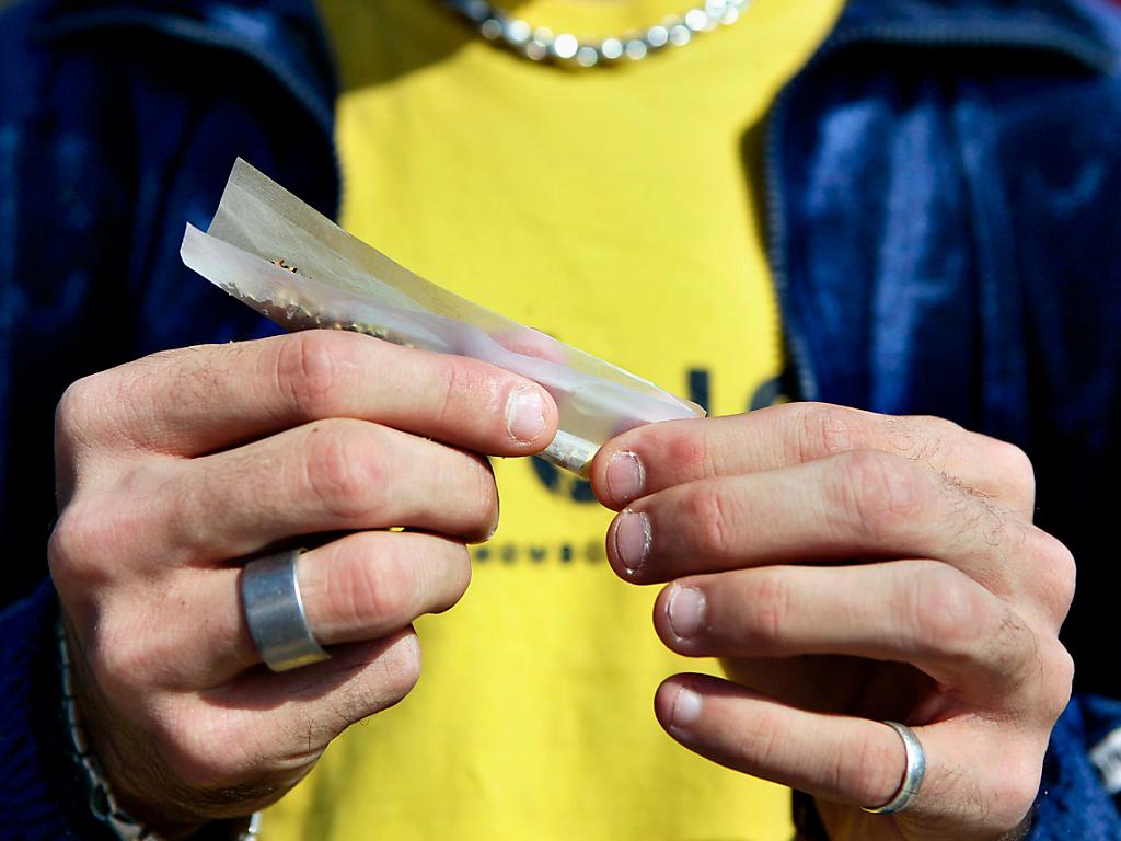 Aufnahme von Händen eines Mannes, die einen Joint drehen.