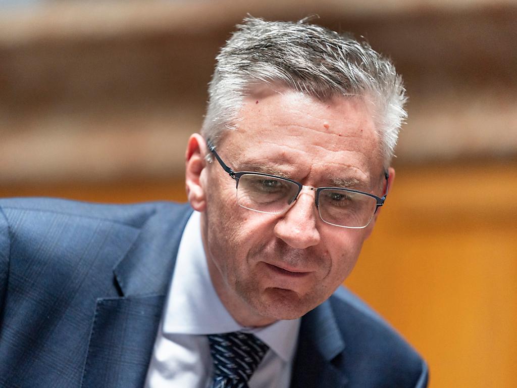Aufnahme eines Mannes mit grauen Haaren und Brille in blauem Anzug.