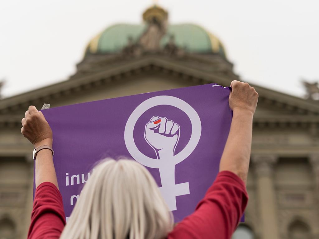 Eine Frau hält an einer Demo ein lila Tuch in die Höhe