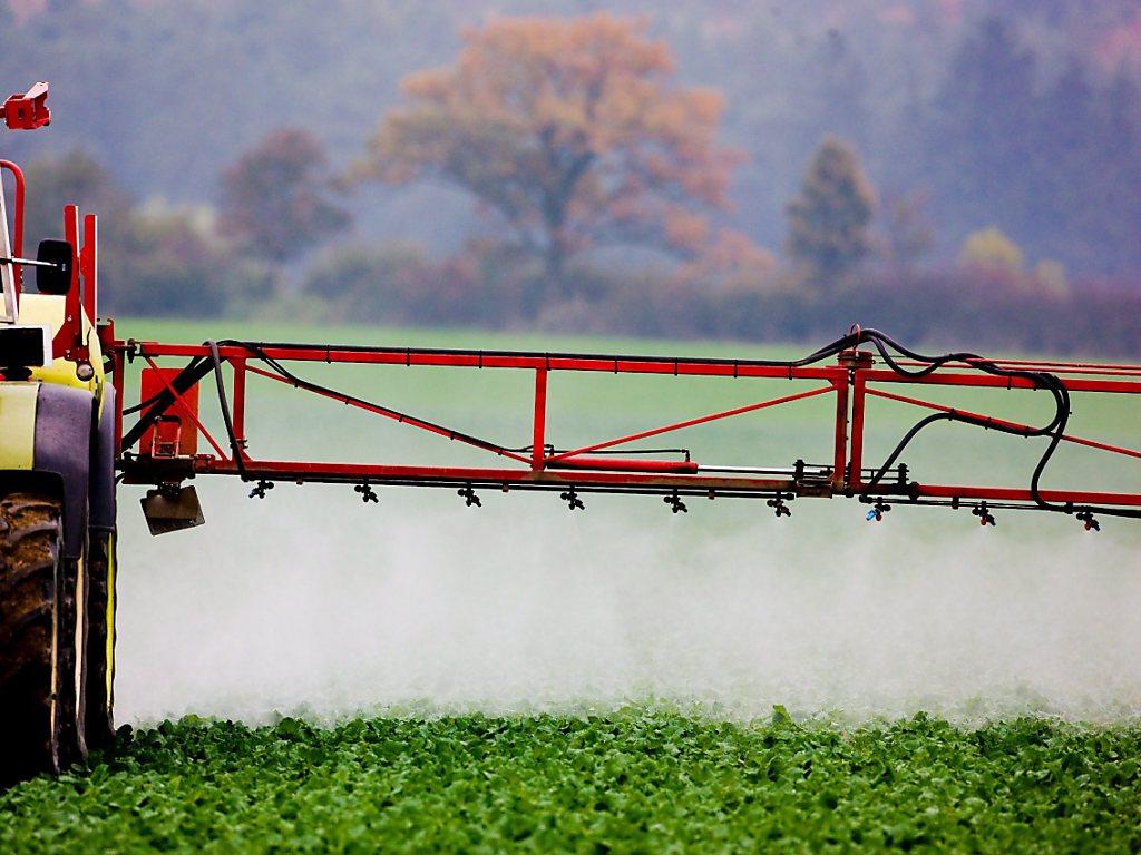 Eine landwirtschaftliche Maschine besprüht ein Feld.