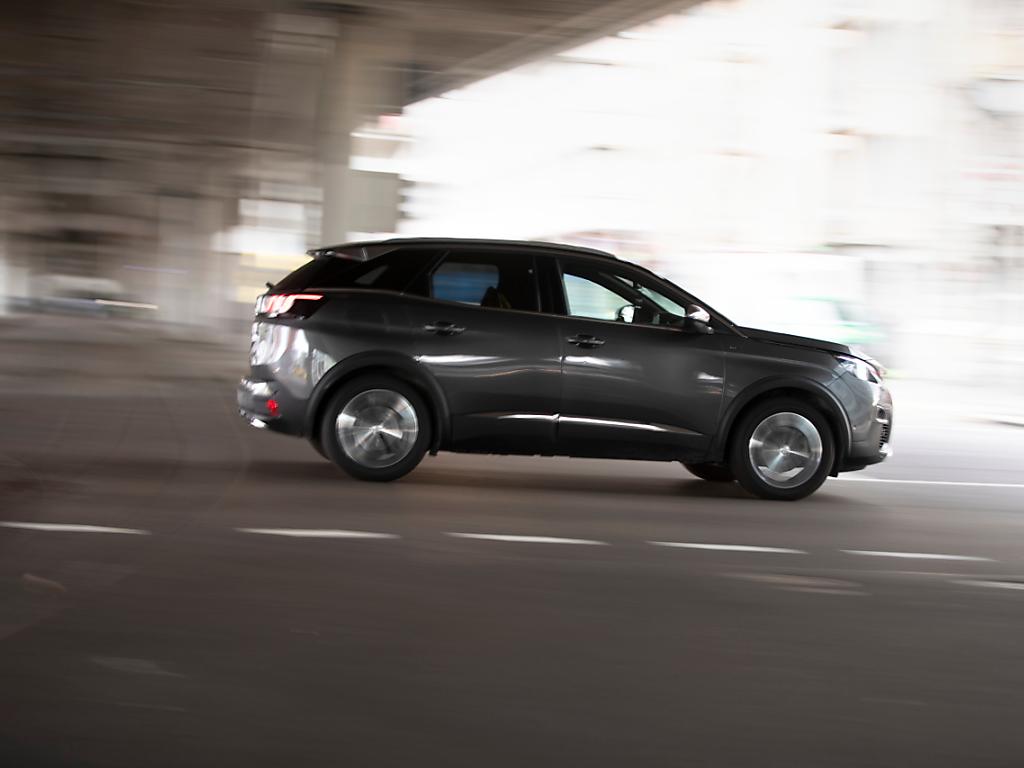 Ein SUV fährt unter einer Unterführung durch.