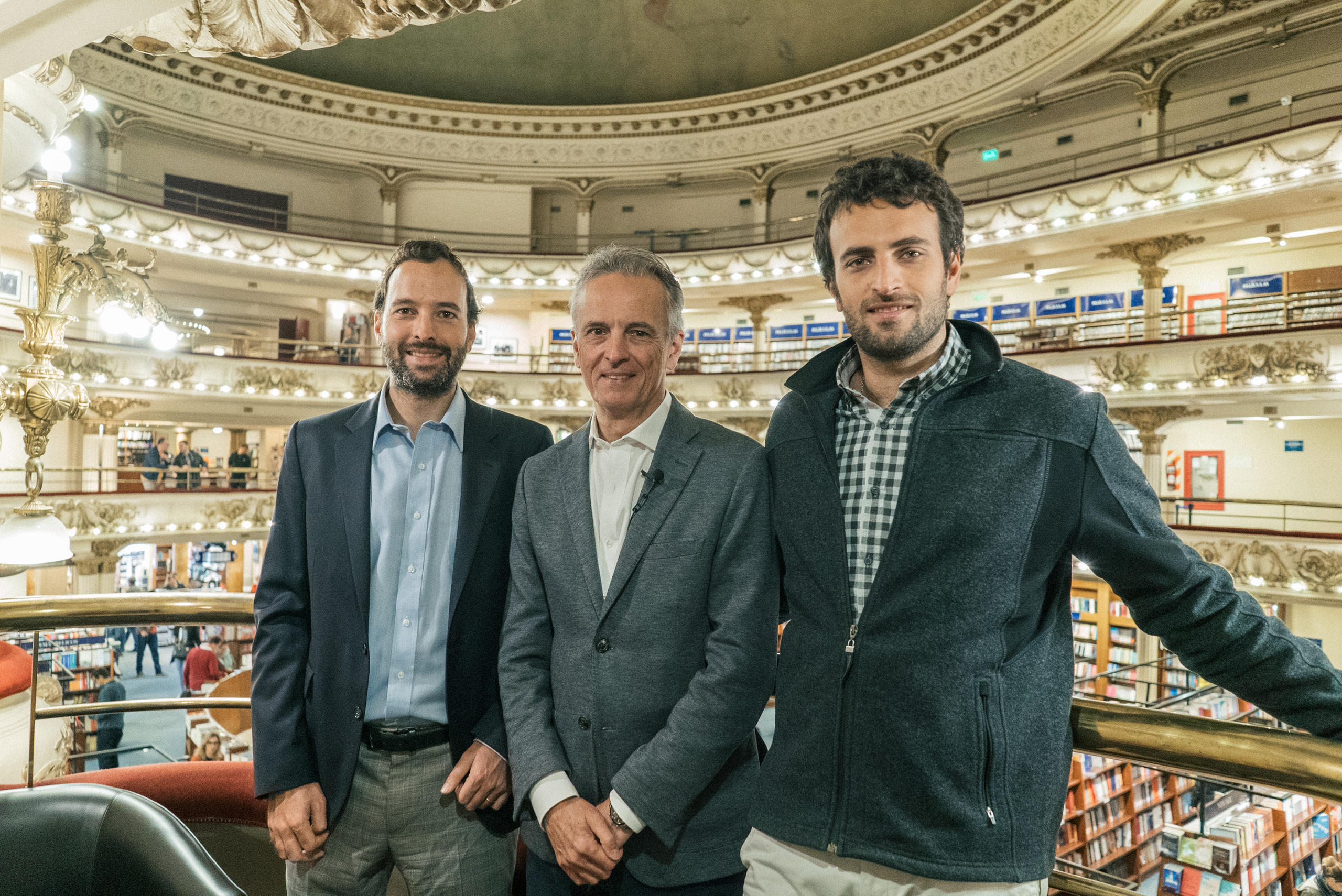 صورة جماعية لثلاثة رجال داخل مكتبة ضخمة