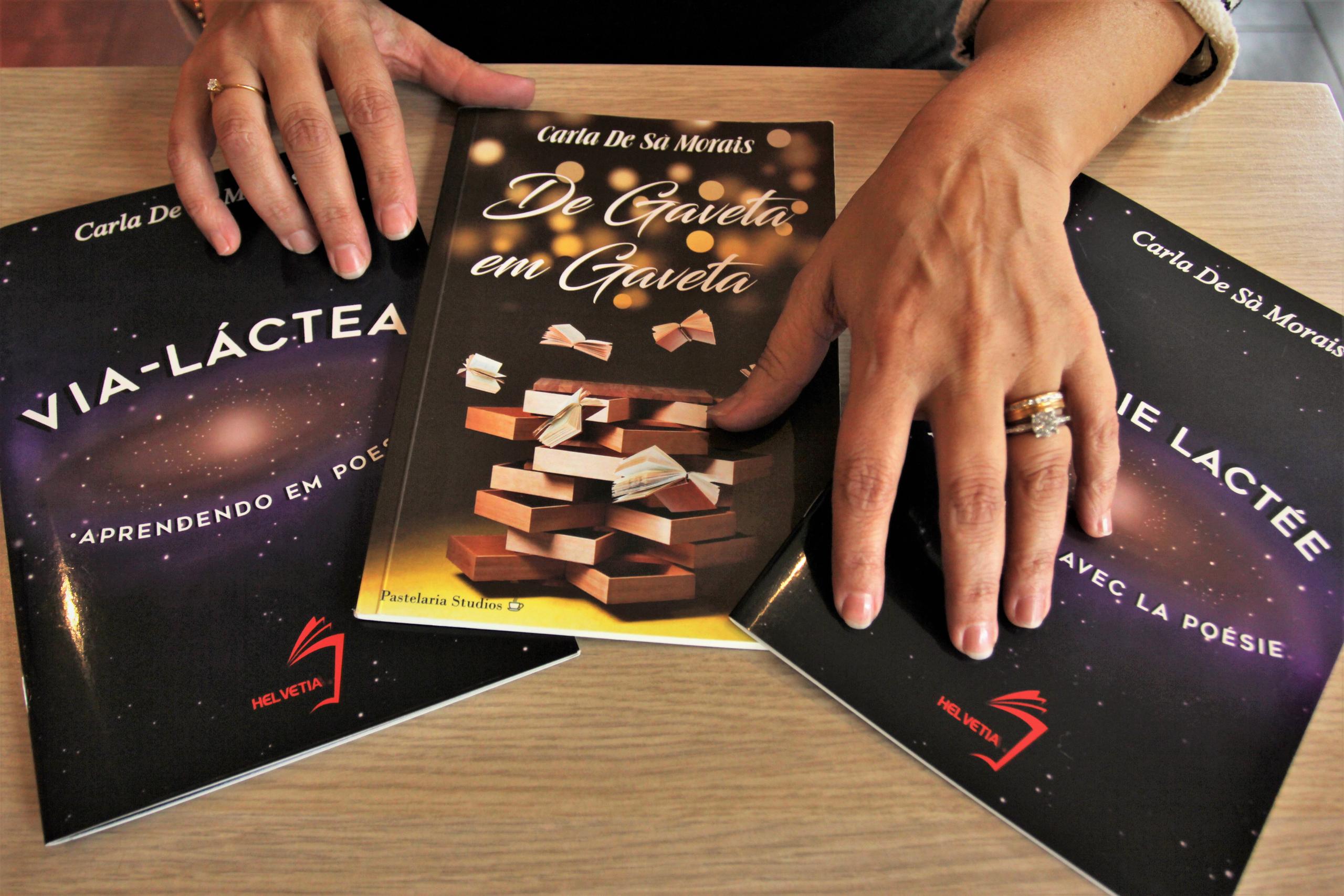 Mão de mulher sobre livros expostos em uma mesa