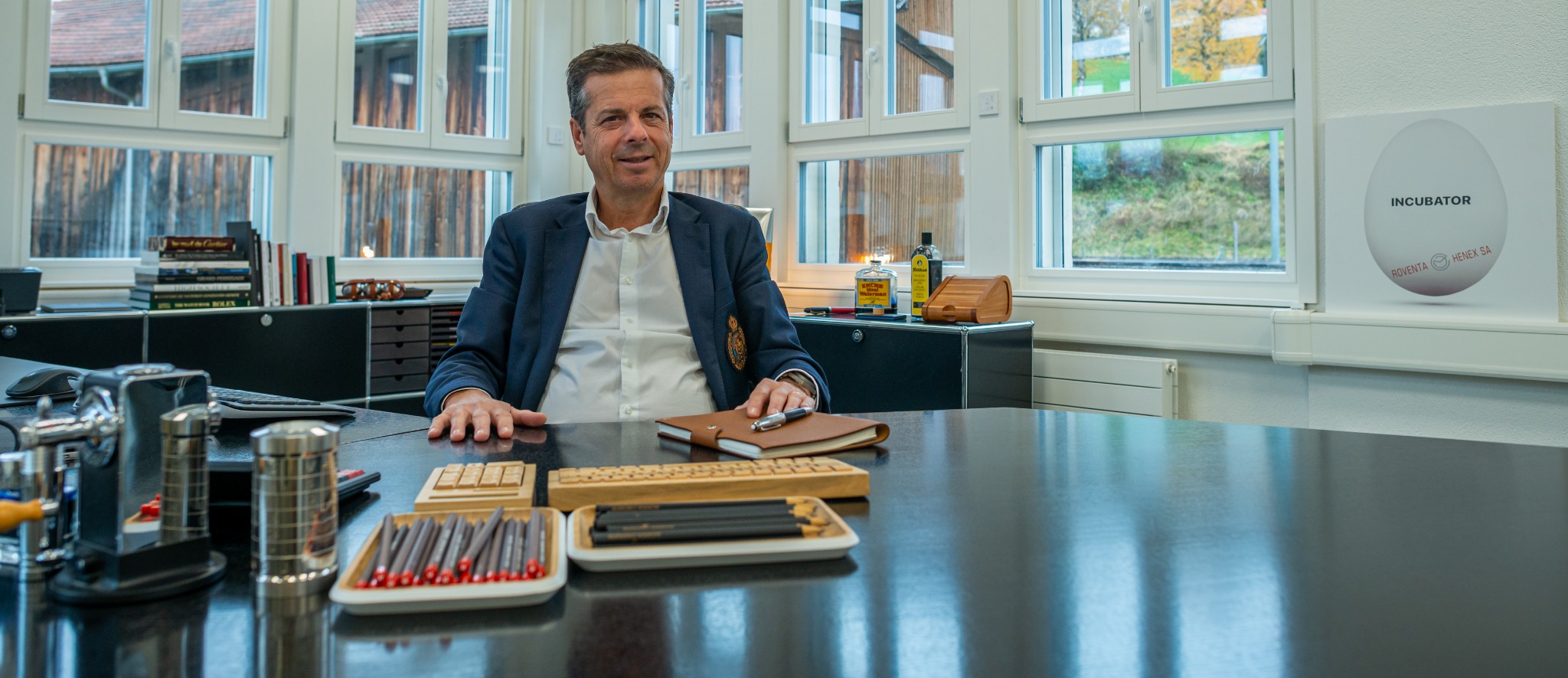 Jérôme Biard sitzt an einem grosszügigen Bürotisc, vor sich gespitzte Bleistifte