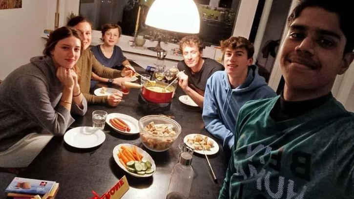 giovani a un tavolo mangiano una fondue al formaggio