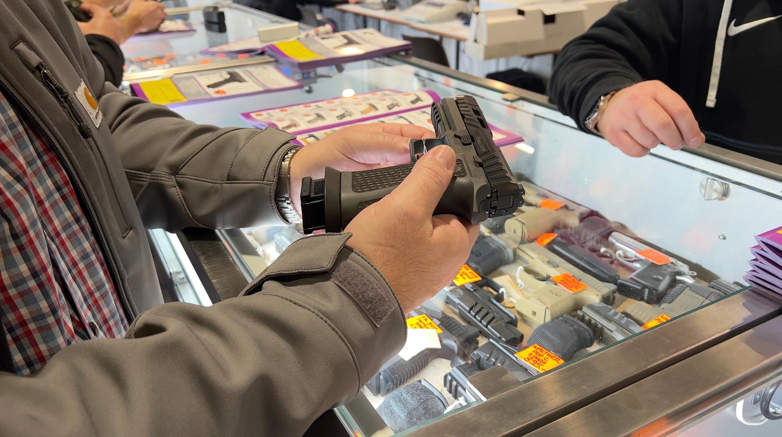 A man holding a gun over a counter at a weapon fair