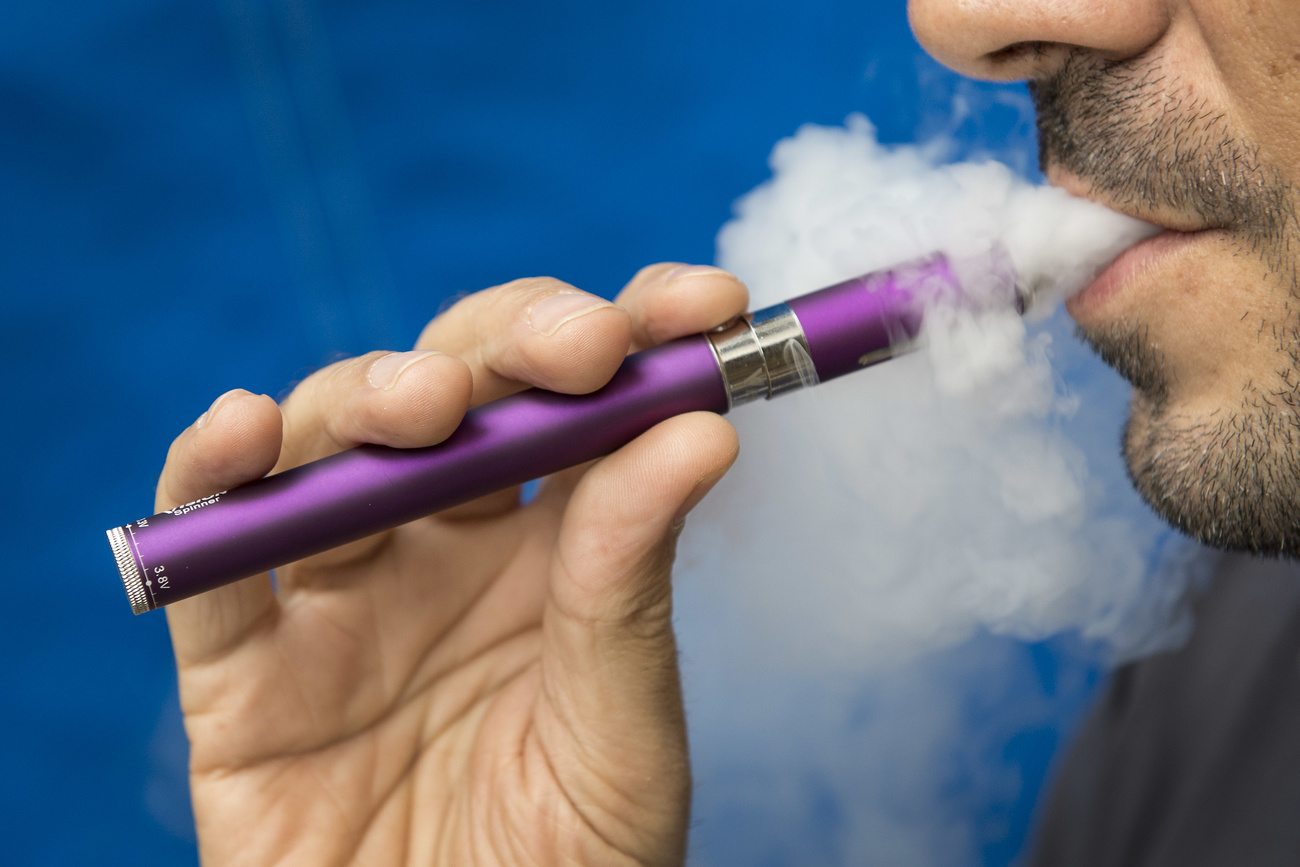 un homme fume une cigarette électronique