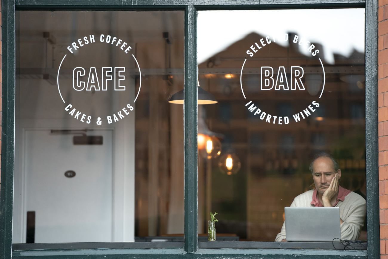 Ein Mann arbeitet an seinem Laptop in einem Café in England