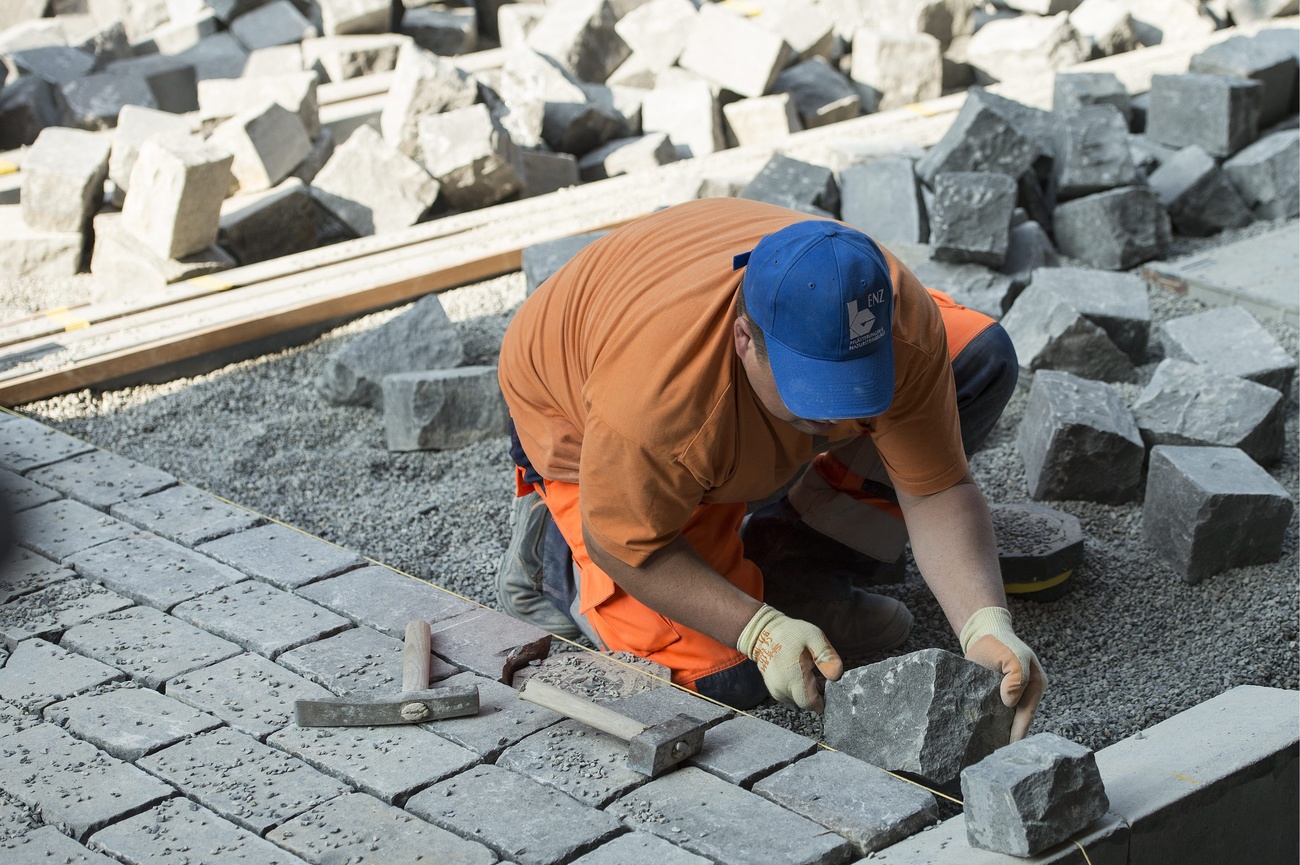 un ouvrier pose des pavés en pierre sur un pont à Berne