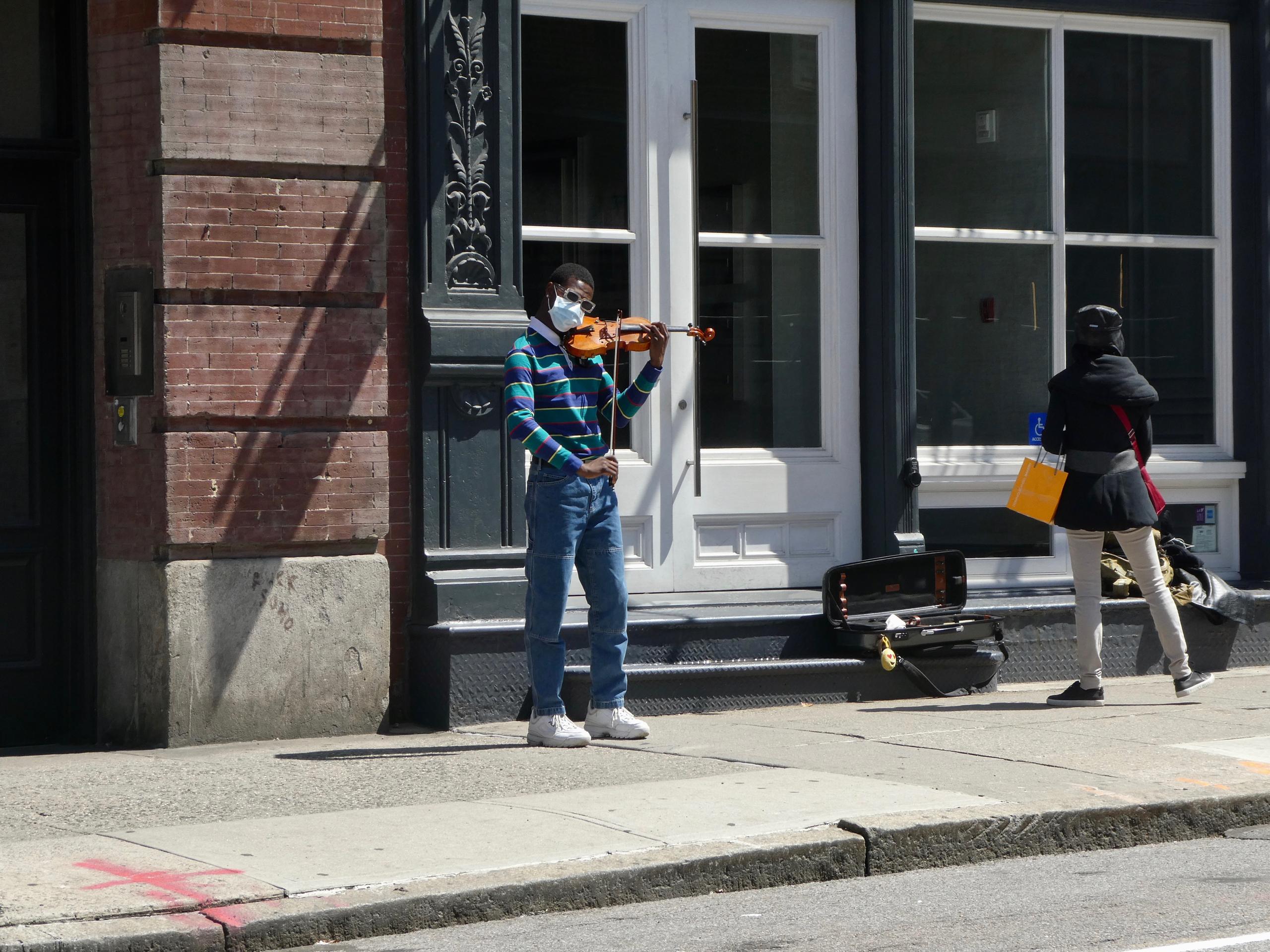 マスク姿でバイオリンを演奏するミュージシャン