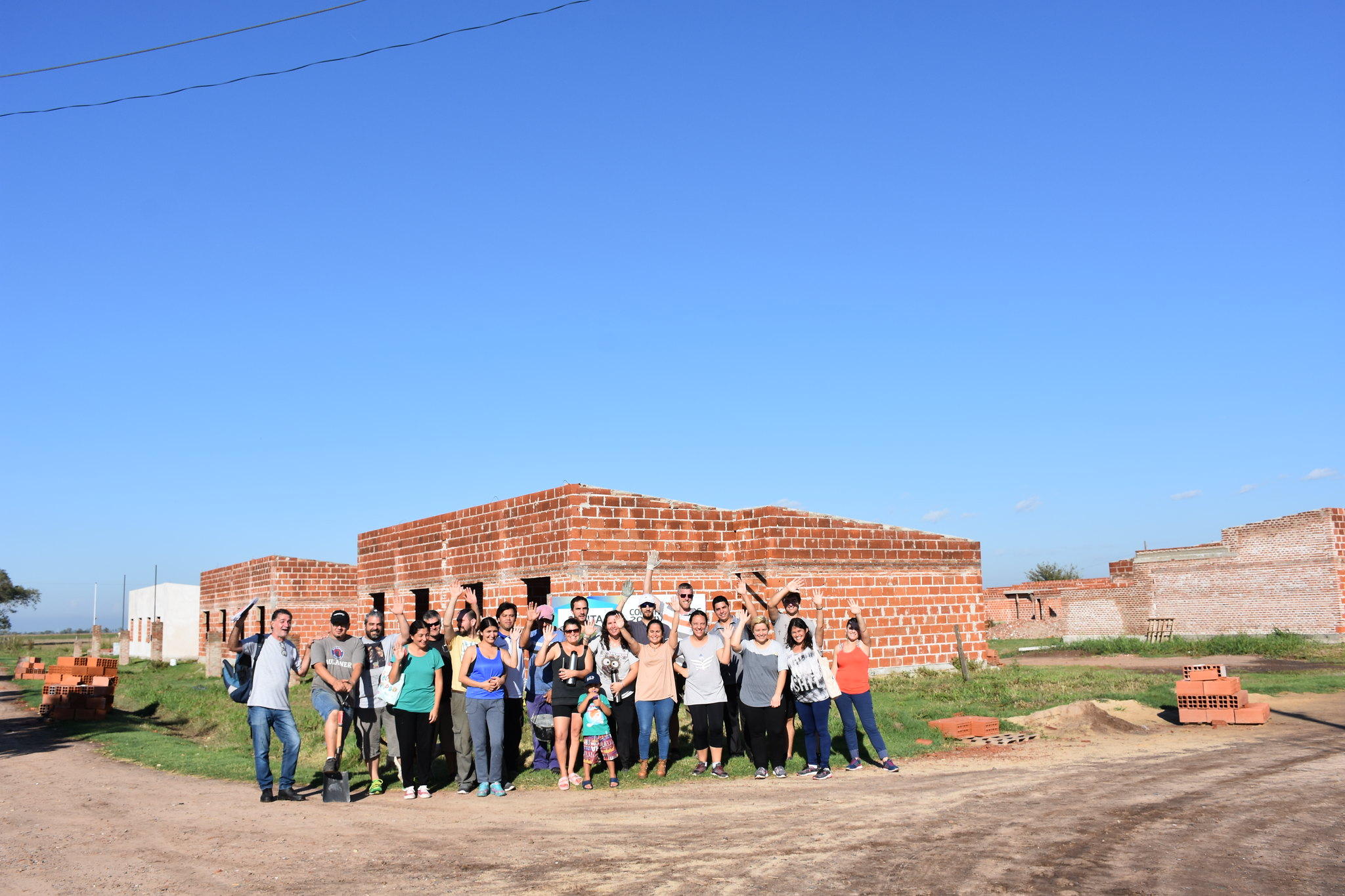 Grupo de personas posan para la foto delante de una casa en construcción.