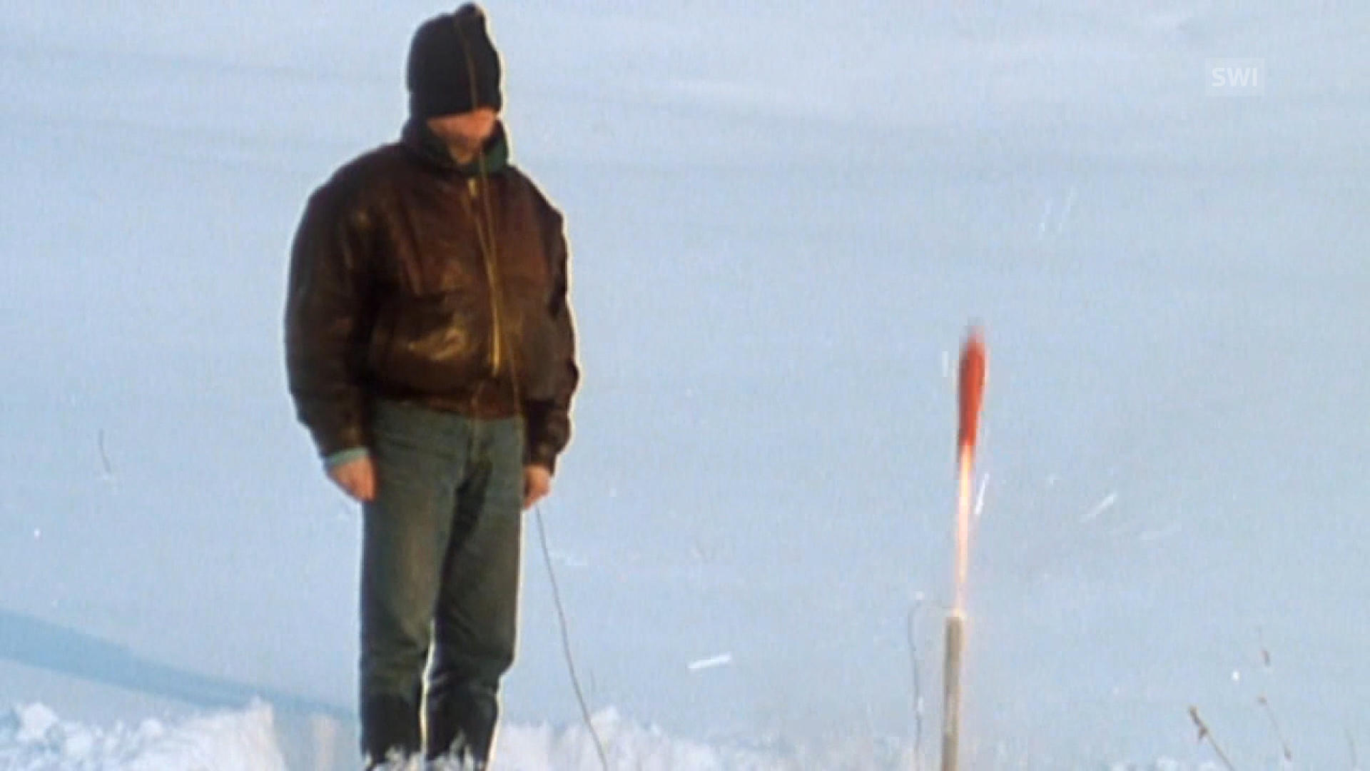 Video still of man standing in snowy field, blindfolded