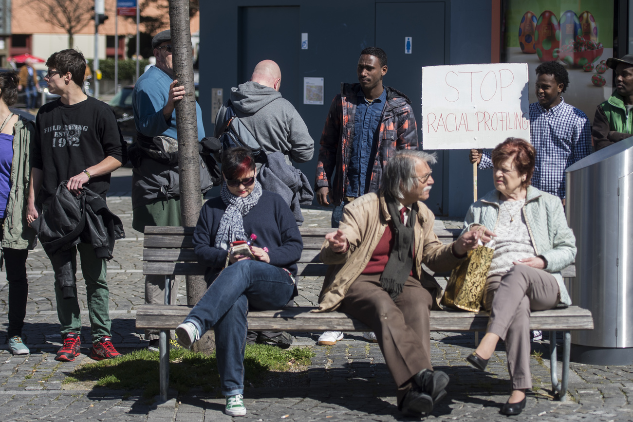 Protest gegen Racial Profiling, während Passant:innen weiter ihren Weg gehen.