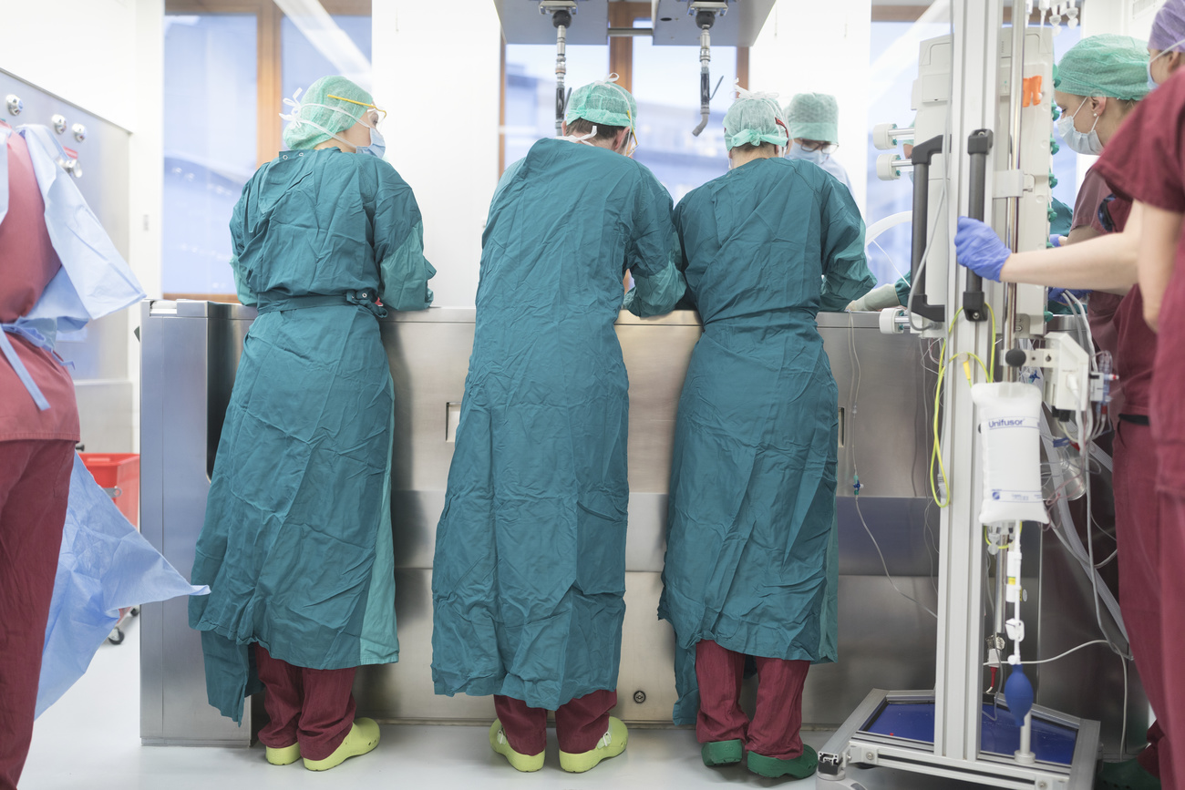 Photo of three doctors looking over a bed with patient