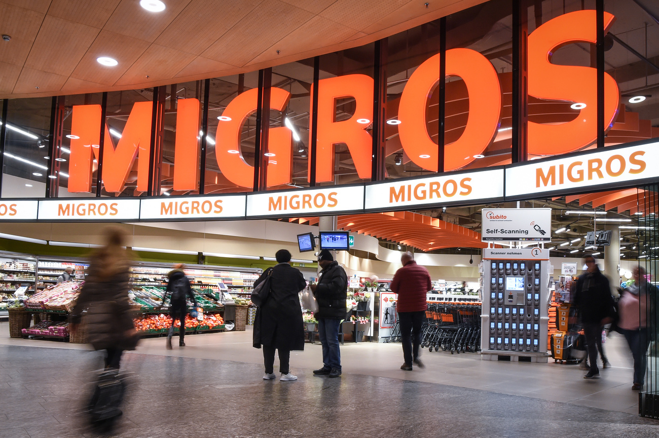 Das Migros Logo beim Ladeneingang