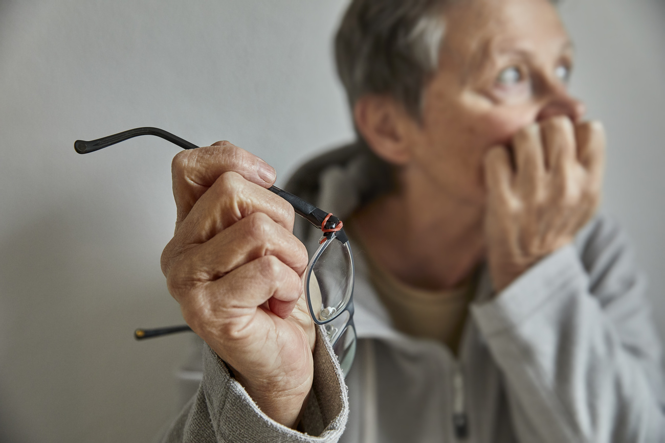 ältere Frau hält Brille in der Hand