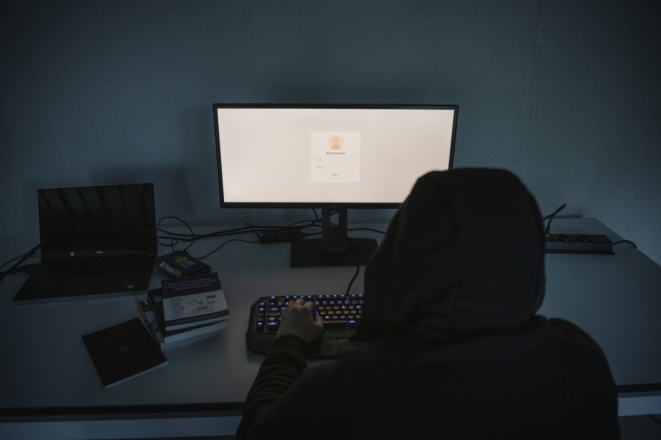 Picture of a person in a black hood in front of a computer