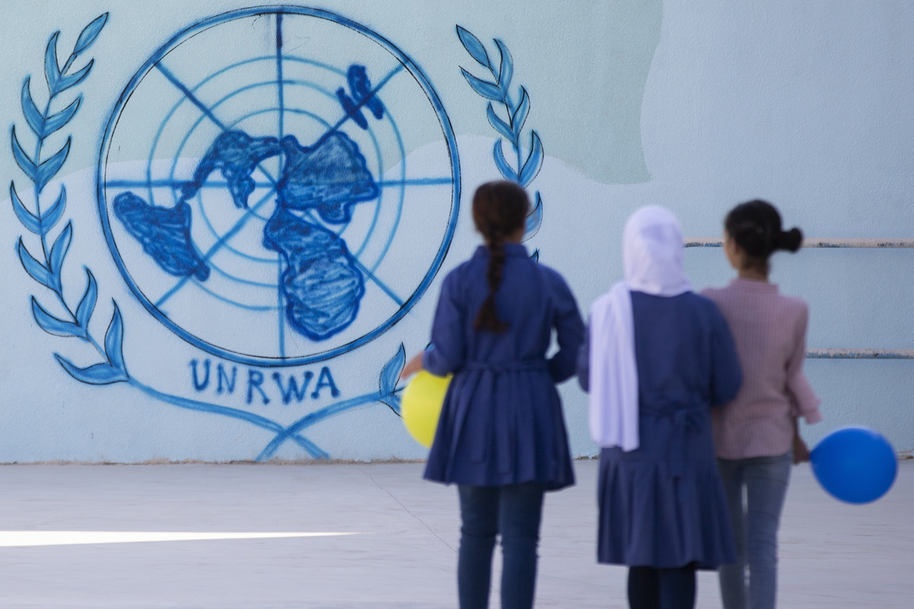 Picture of young girls in front of UNRWA logo on wall