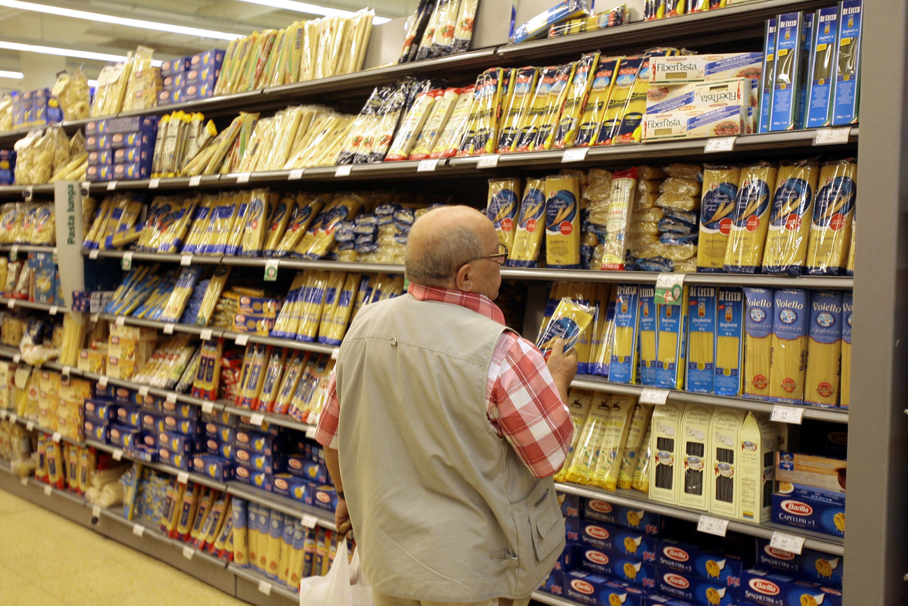 persona davanti a uno scaffale di un supermercato riempito di pasta