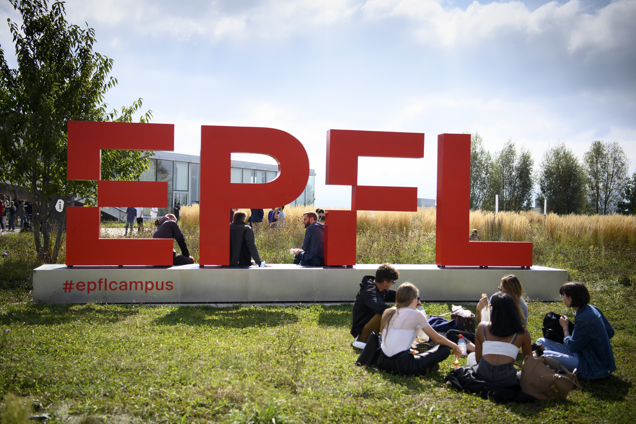 studenti seduti in un prato davanti a scritta EPFL