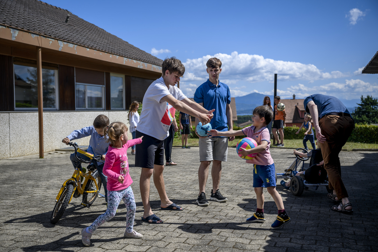 children and adults from the Marioupol region play in the courtyard of the tipiti project in Gilly