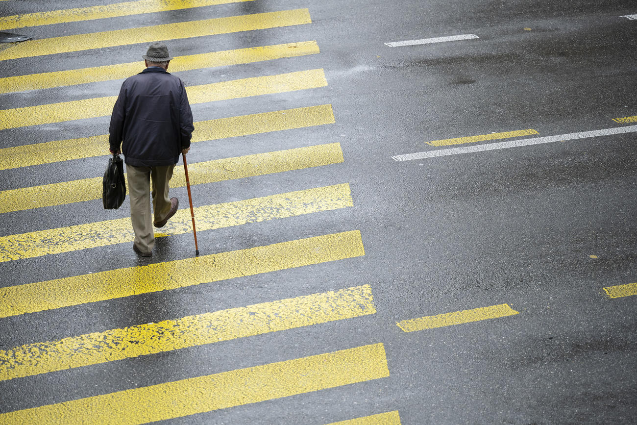 un anziano attravesra la strada sulle strisce pedonali