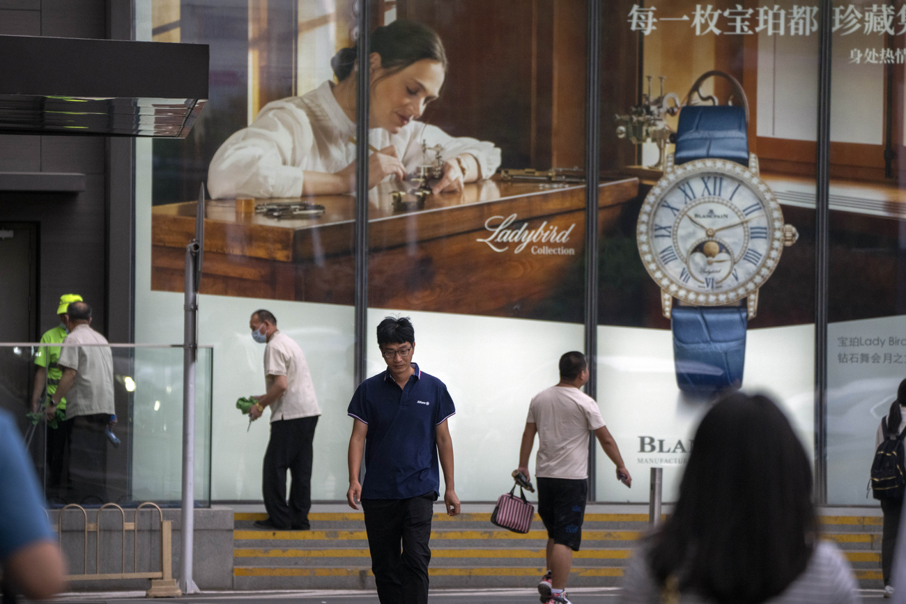 People walk past a billboard for Swiss luxury watch retailer.