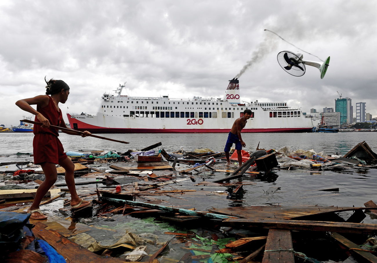 Photo of two young people collecting belongings in harbour after a typhoon.