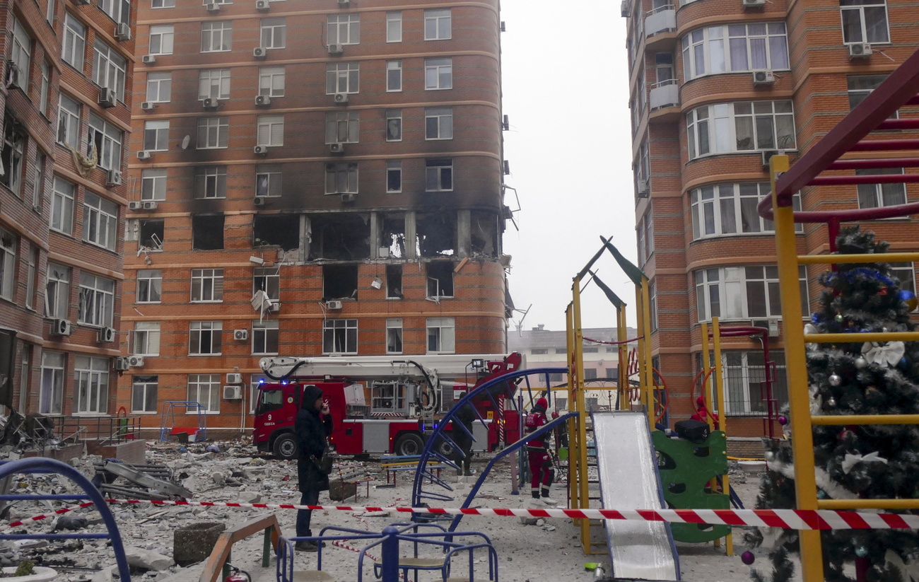 edificio semidistrutto con pompieri al lavoro
