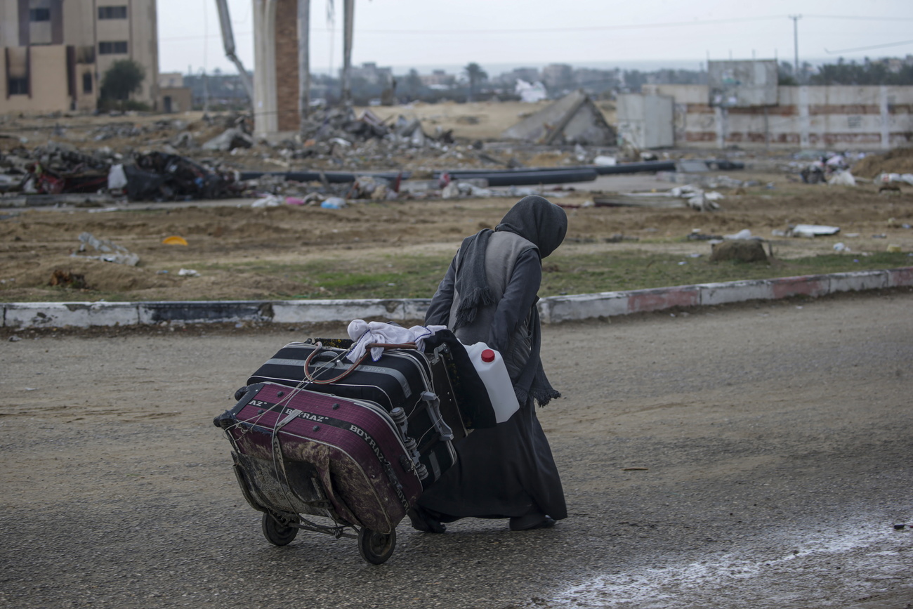 donna palestinese trascina carrello con alcune valigie