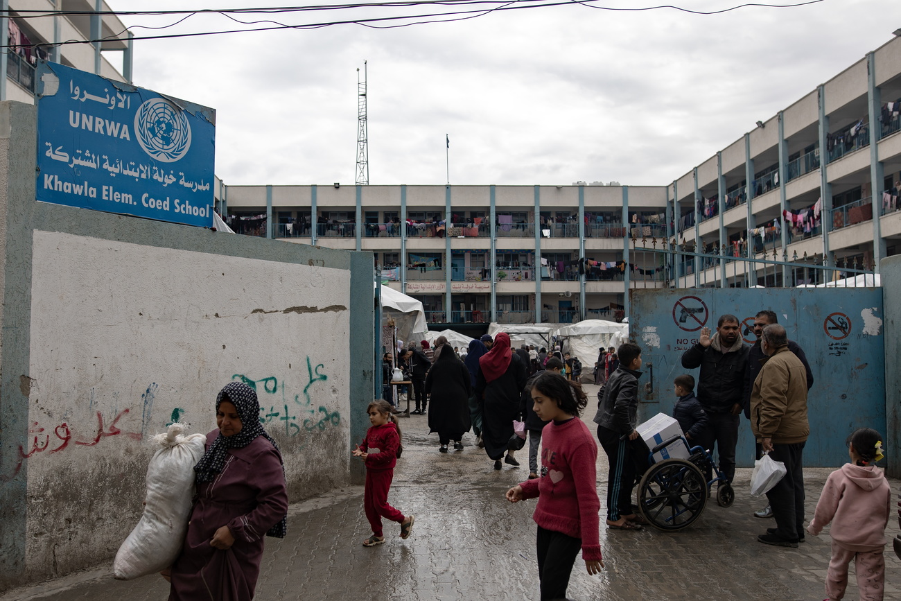 Personen vor einer Schule in Gaza - tristes Betongebäude, Stromleitungen