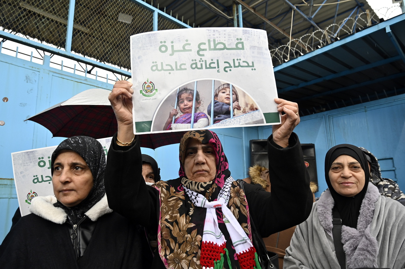 Palestinian women holding a placard with Arabic text.