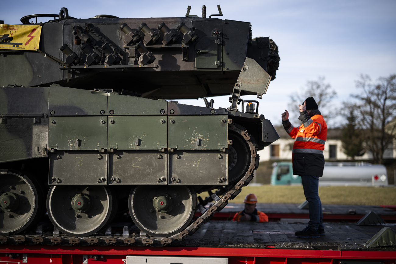 Ein Mann dirigiert das Verladen eines Panzers auf einen Zug