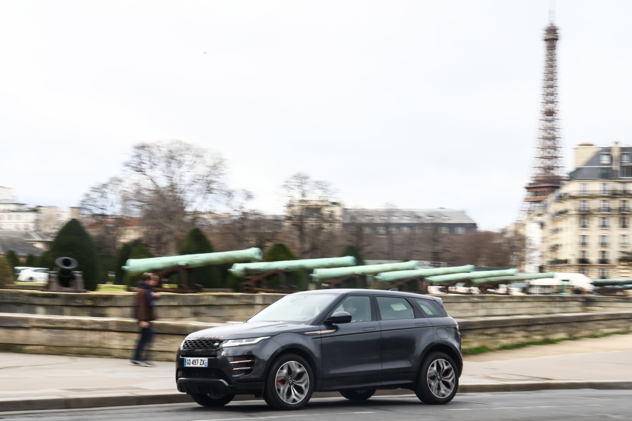 suv circola su una strada e tour eiffel sullo sfondo