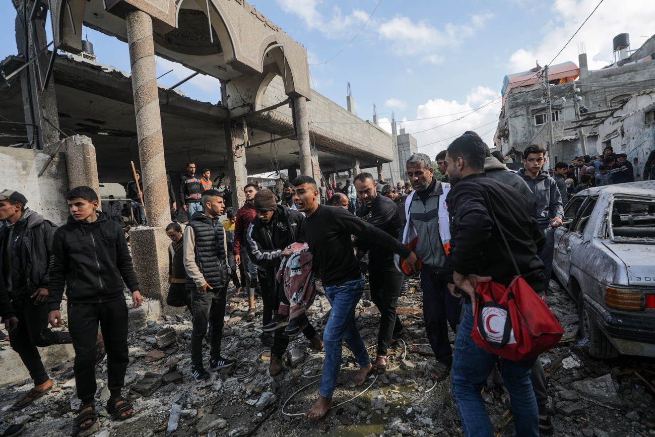 Palestinians carry a body from the rubble of a destroyed mosque in Deir Al Balah town, Gaza Strip,