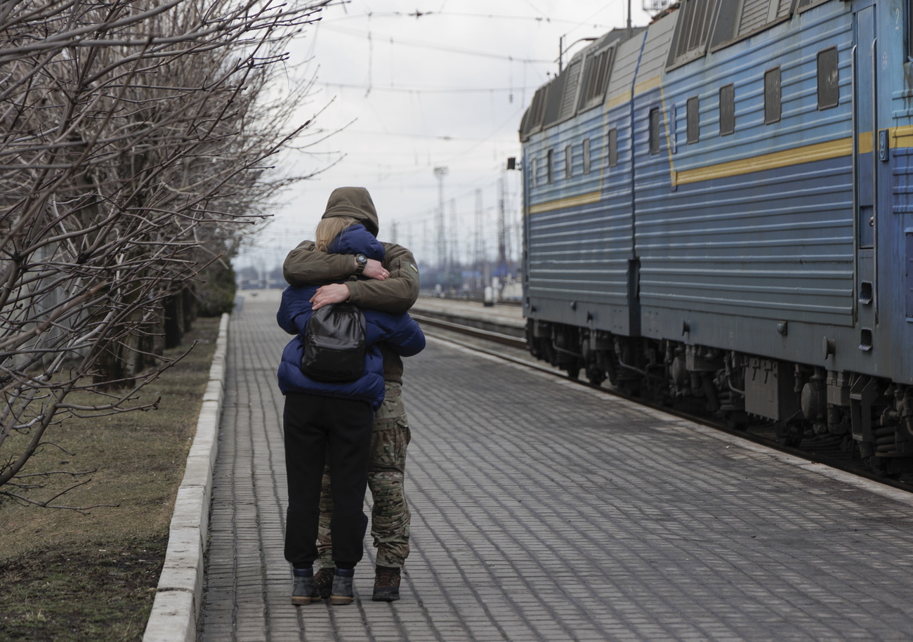 two people embracing in front of a train with ukrainian colours
