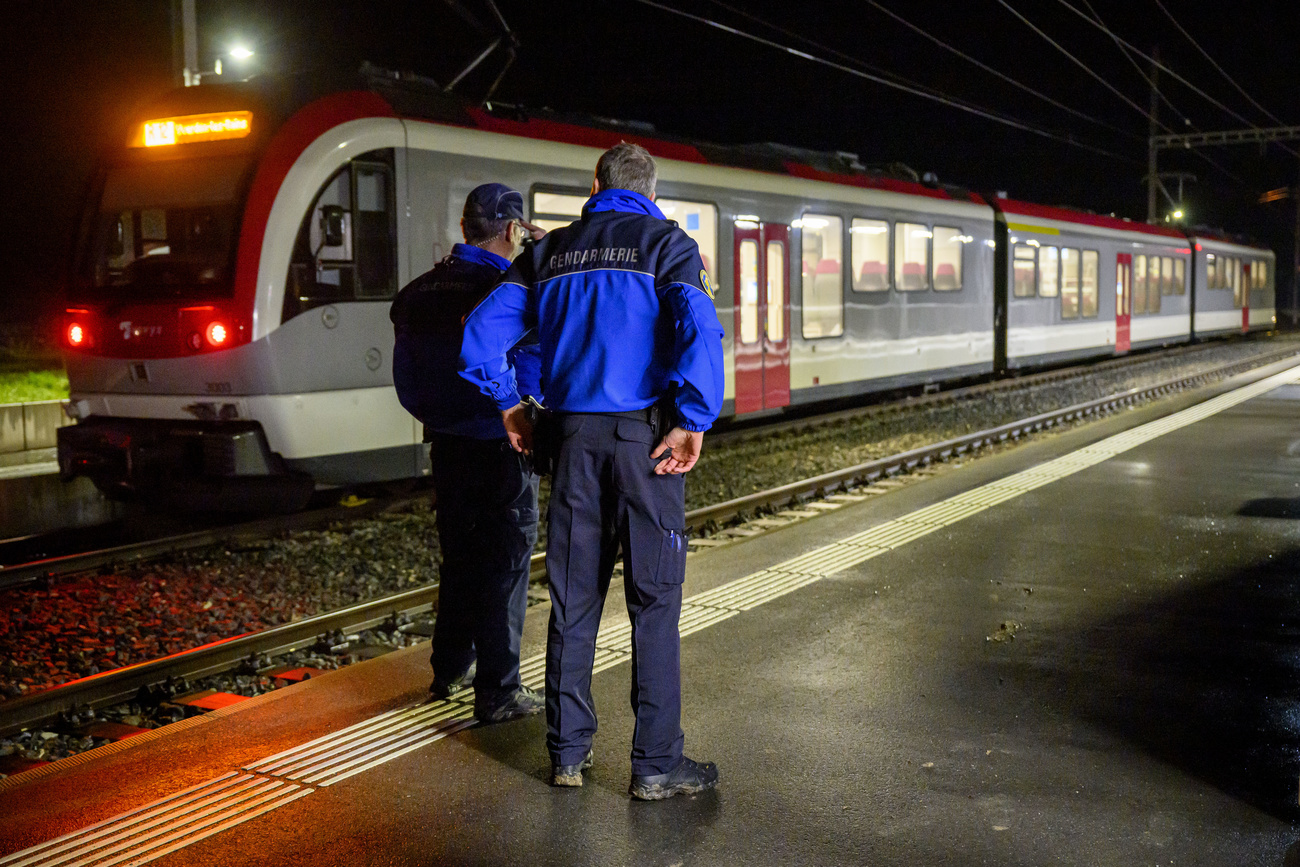 Due agenti della polizia cantonale vodese davanti al treno, teatro della presa d ostaggi.