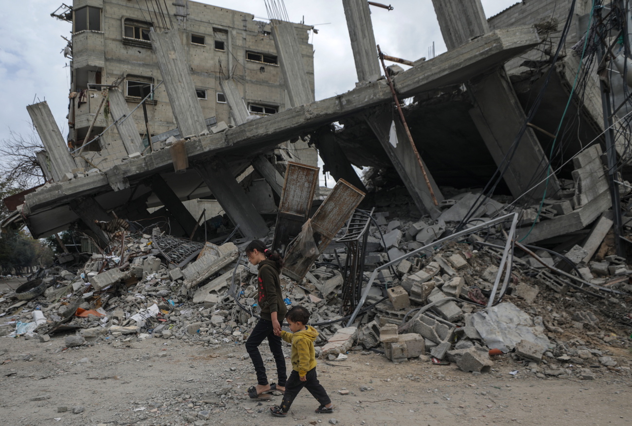 Due minorenni camminano tra le macerie a Gaza.