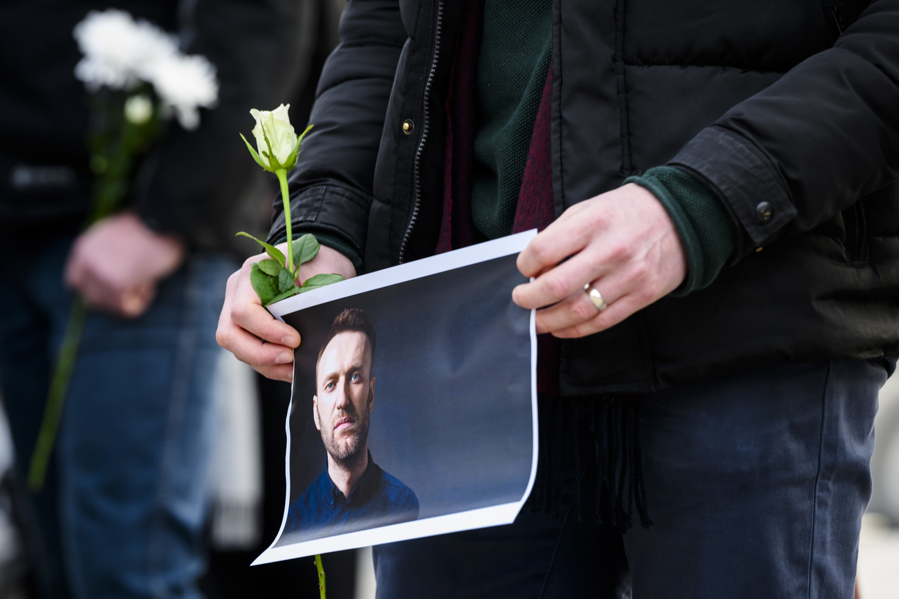 Una persona sosteniendo una foto de Navalni y una flor