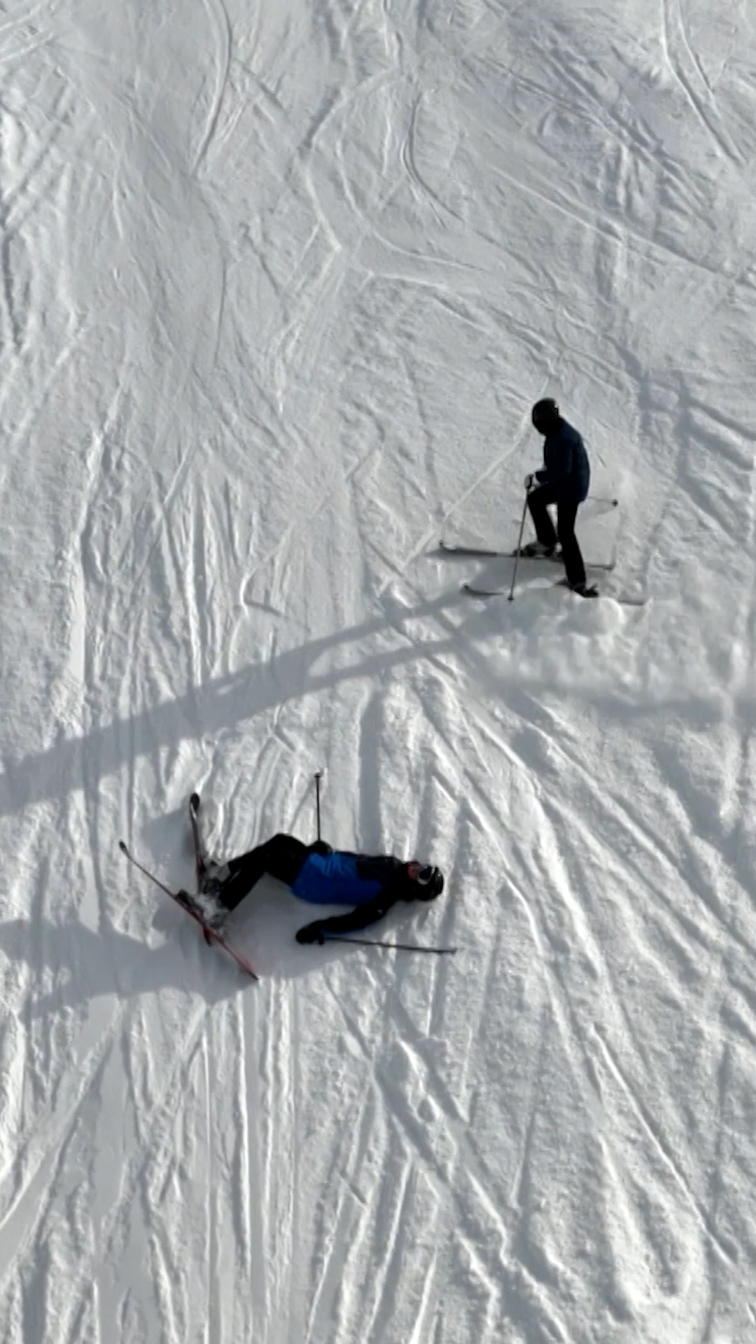Skifahrer auf der Piste, einer am Boden.