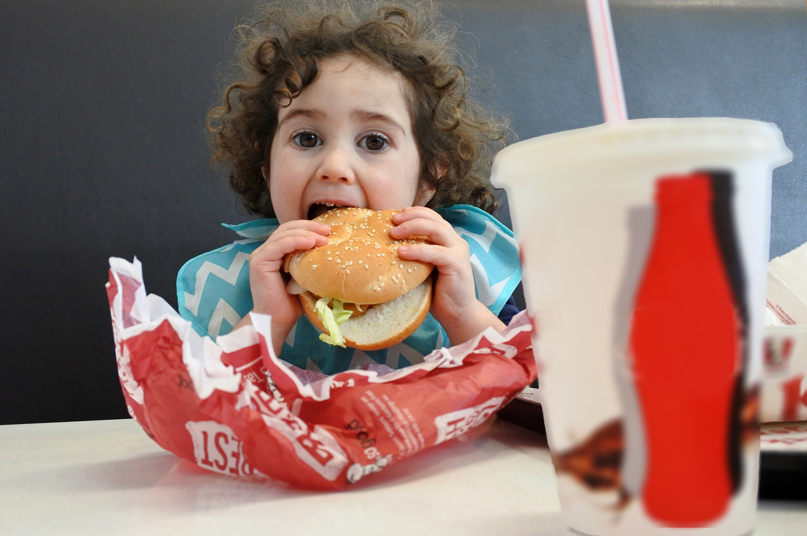 bambina che mangia un hamburger
