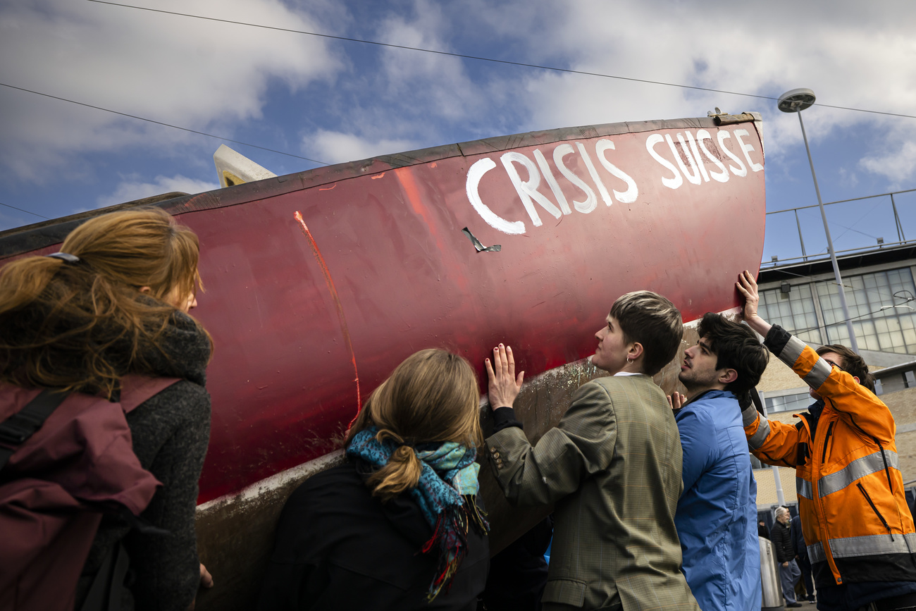 Protesters lift a boat with the title Crisis Suisse