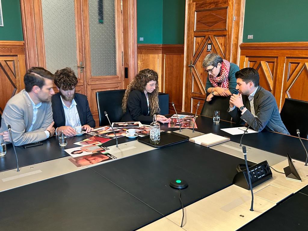 Cinq personnes assises à une table au Palais fédéral