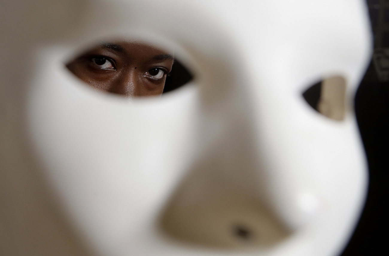 Person peers through eye of a mask
