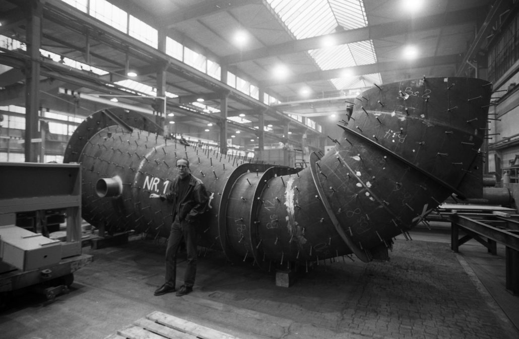Arbeiter vor einem riesigen Metallrohr