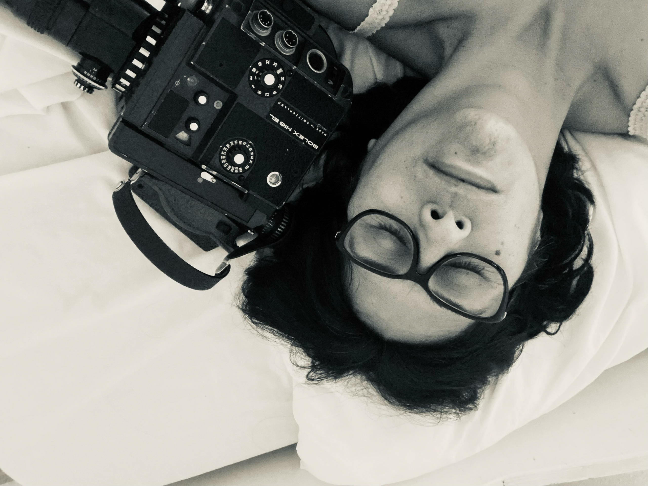 Jeannette Muñoz, liegend von oben fotografiert, neben sich eine Filmkamera