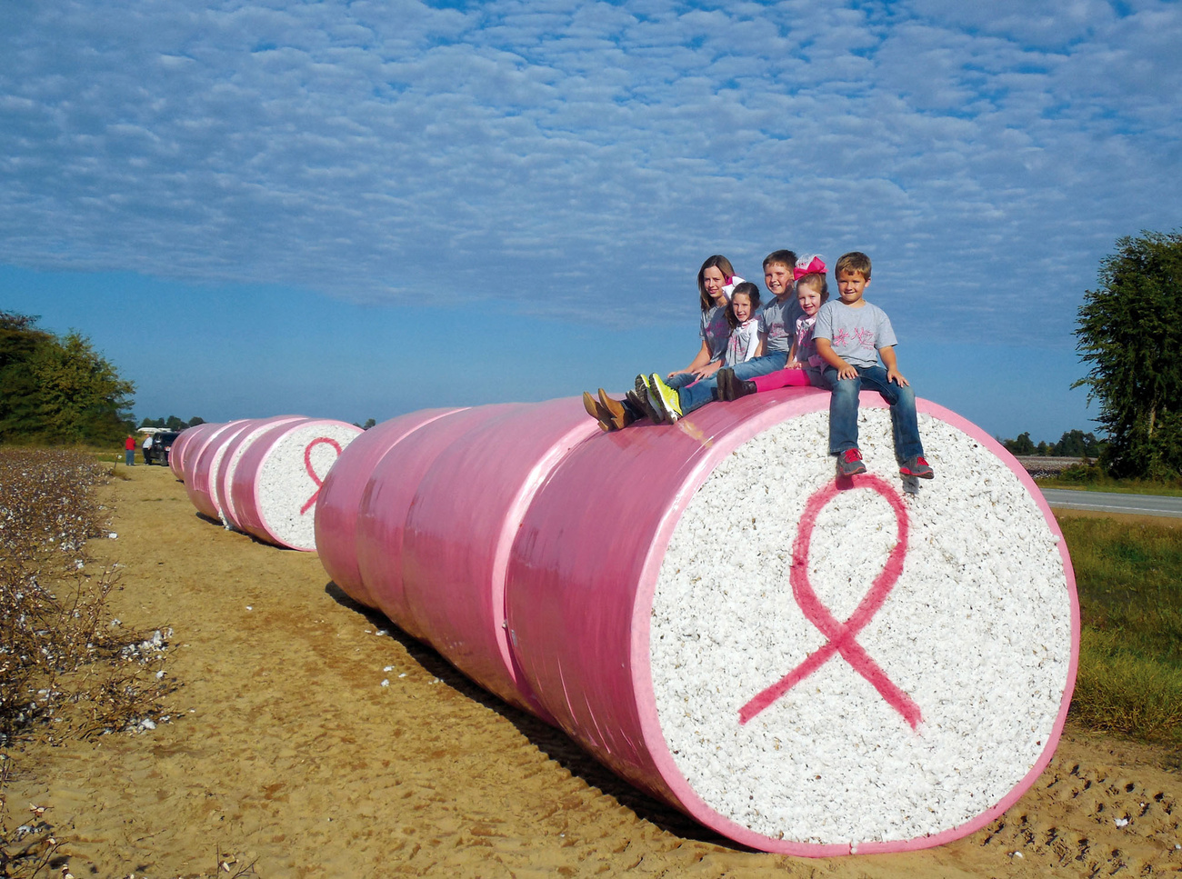 bambini seduti su delle balle di cotone per una campagna di sensibilizzazione al tumore al seno