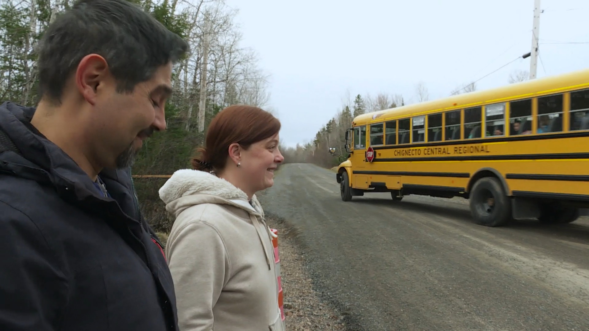 Paar auf einer Strasse mit gelbem Schulbus, der hinter ihnen losfährt